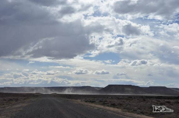 Estrada de rípio que nos leva ao Bosque Petrificado, região de Caleta Olivia, no sul da Argentina. A linha de poeira ao fundo é um carro se movimentando